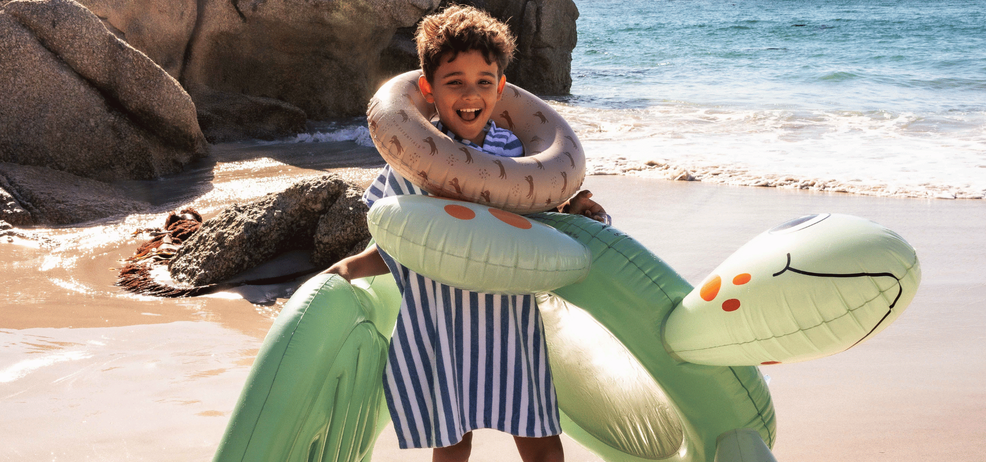 happy child on beach with inflatable turtles and other beach inflatables